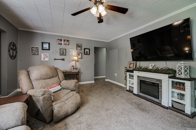 carpeted living area with baseboards, a fireplace, a ceiling fan, and ornamental molding