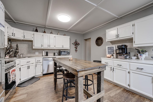 kitchen with light wood finished floors, tasteful backsplash, white cabinets, and appliances with stainless steel finishes