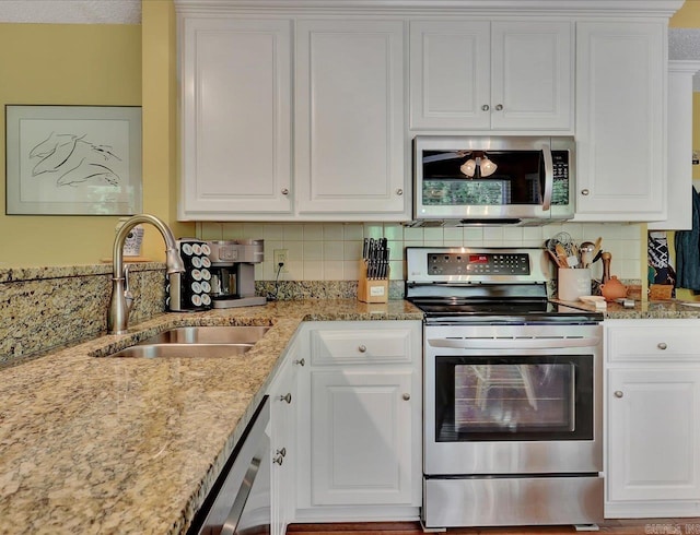 kitchen featuring white cabinets, backsplash, appliances with stainless steel finishes, and a sink