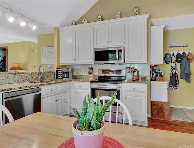 kitchen with white cabinetry, decorative backsplash, appliances with stainless steel finishes, and a sink