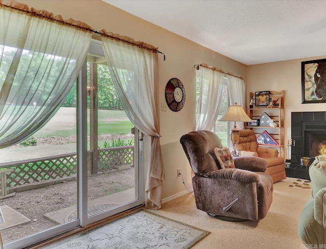 sitting room with a tile fireplace, carpet, and baseboards