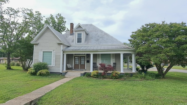 320 E 4th St, Lonoke, AR 72086 - view of front of house featuring a chimney, french doors, metal roof, covered porch, and a front yard