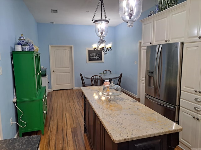320 E 4th St, Lonoke, AR 72086 - kitchen featuring a notable chandelier, a kitchen island, visible vents, stainless steel fridge with ice dispenser, and wood finished floors