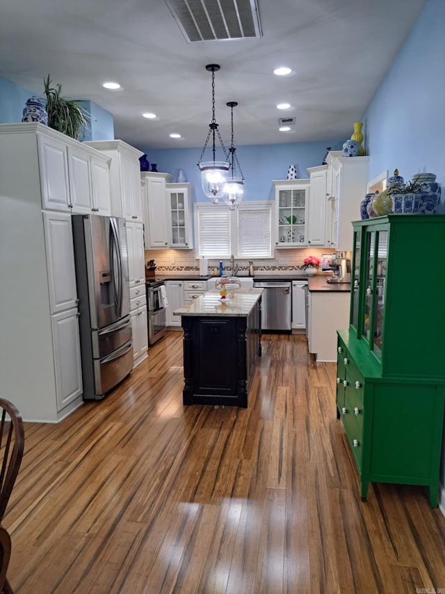320 E 4th St, Lonoke, AR 72086 - kitchen with decorative light fixtures, a center island, glass insert cabinets, white cabinets, and appliances with stainless steel finishes