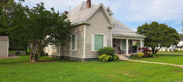 320 E 4th St, Lonoke, AR 72086 - view of front facade featuring covered porch, a chimney, and a front lawn