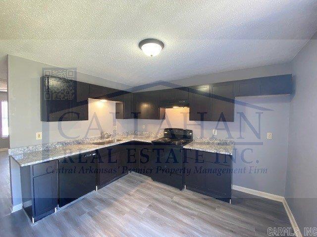 5732 Camp Robinson Rd, North Little Rock, AR 72118 - kitchen with light wood-style flooring, a textured ceiling, stove, baseboards, and light stone counters