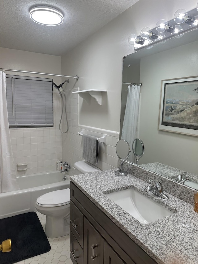 full bathroom with toilet, vanity, a textured ceiling, wainscoting, and shower / tub combo