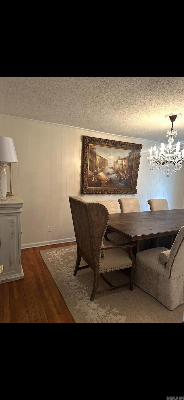 dining space with an inviting chandelier, a textured ceiling, and hardwood / wood-style flooring