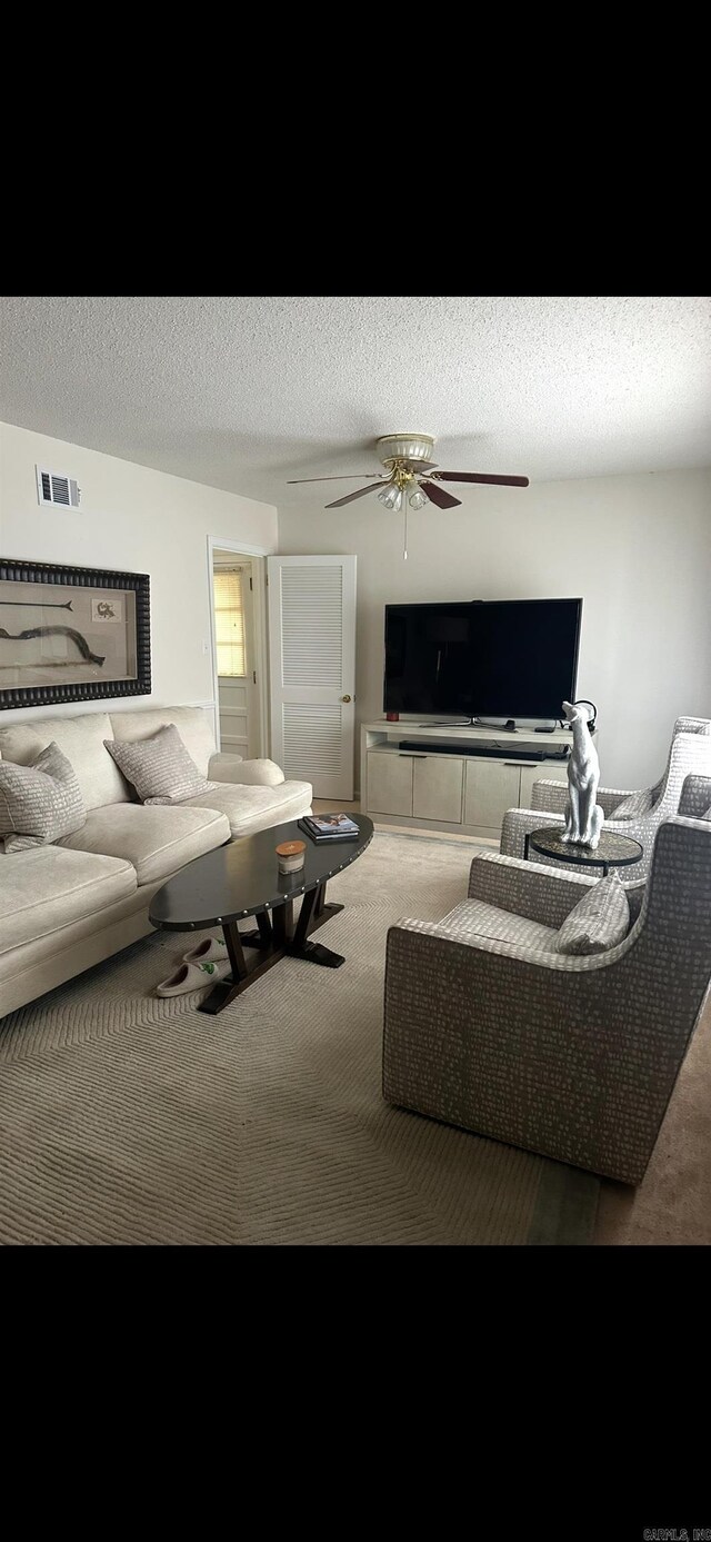 living room featuring carpet flooring, a ceiling fan, and visible vents