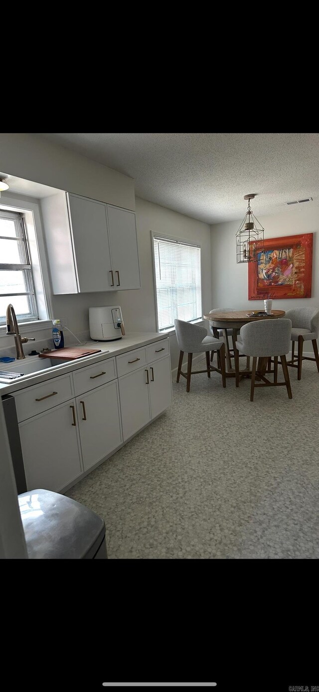 kitchen featuring a sink, light countertops, white cabinets, and a textured ceiling