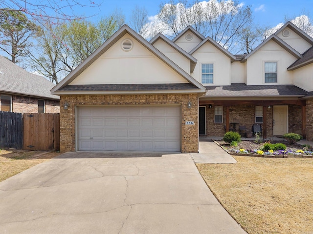 traditional-style home with a porch, fence, brick siding, driveway, and stucco siding