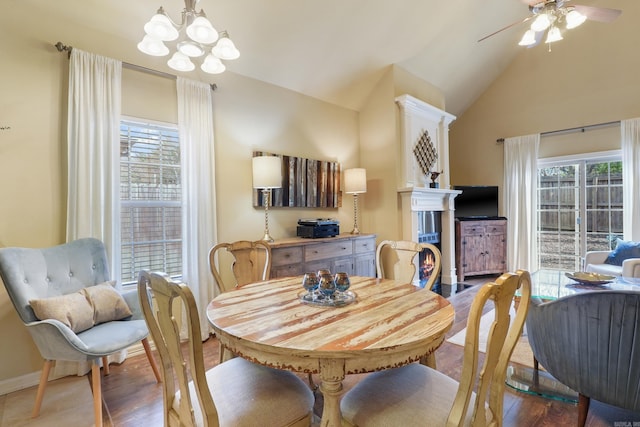 dining area with lofted ceiling, baseboards, ceiling fan with notable chandelier, and wood finished floors