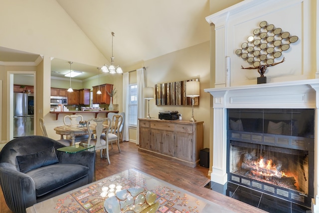 living room with ornamental molding, vaulted ceiling, a tile fireplace, and wood finished floors