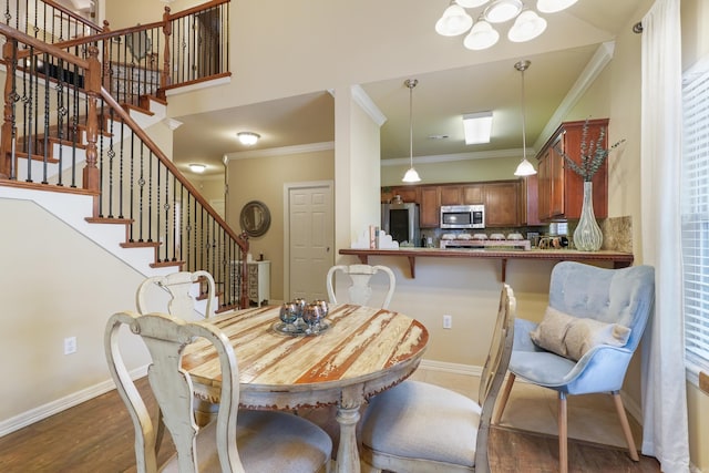 dining room featuring baseboards, stairs, crown molding, and wood finished floors