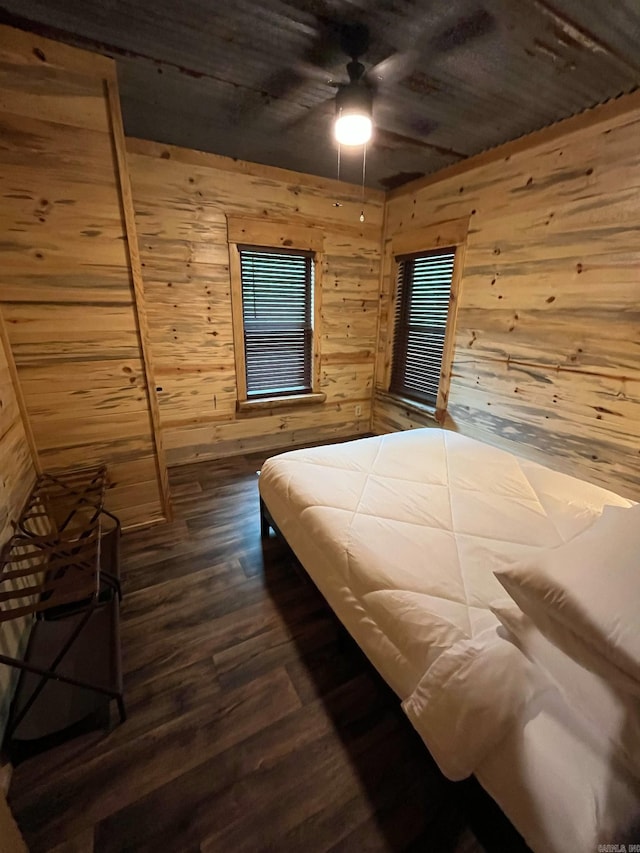 892 Hwy 375 E, Mena, AR 71953 - bedroom featuring wood walls, a ceiling fan, and dark wood-type flooring