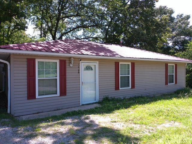 ranch-style home with metal roof and a front lawn