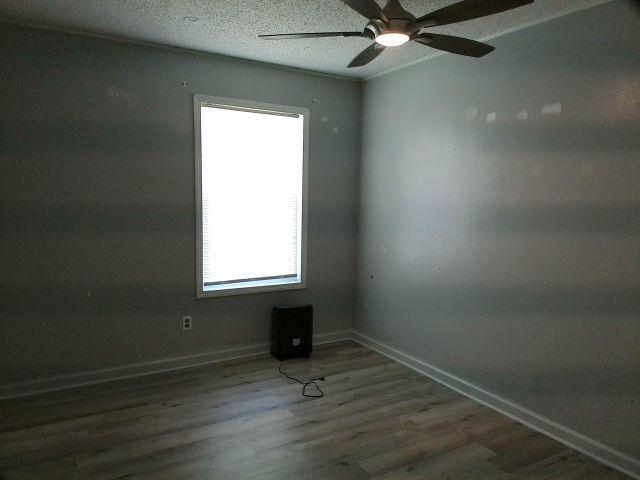 unfurnished room featuring baseboards, a textured ceiling, a ceiling fan, and wood finished floors