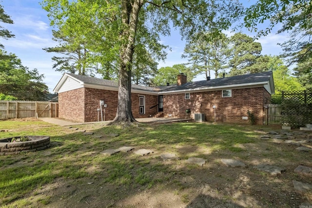 705 Oak St, Beebe, AR 72012 - back of property featuring an outdoor fire pit, cooling unit, a chimney, a fenced backyard, and brick siding