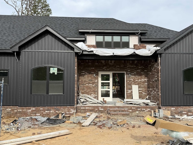 back of property with brick siding and a shingled roof