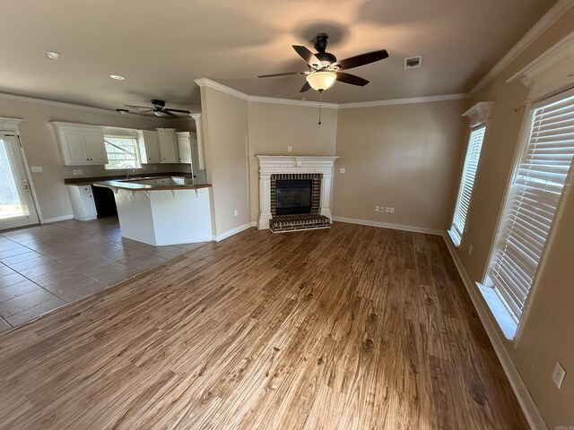 13506 Dynasty Dr, Alexander, AR 72002 - unfurnished living room featuring a fireplace, ceiling fan, visible vents, and wood finished floors