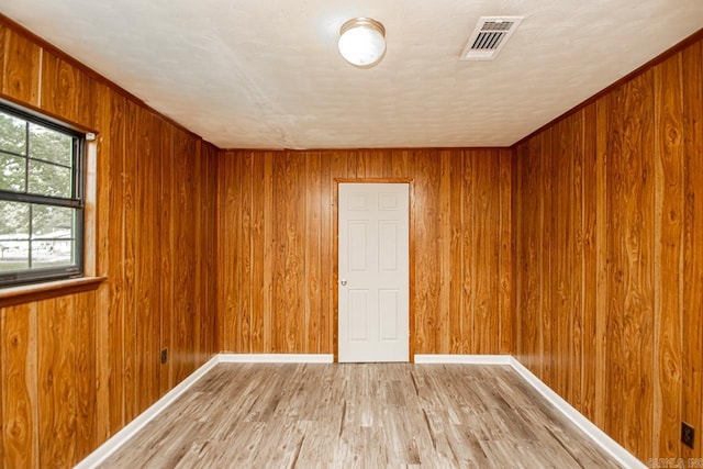 1400 S Rose St, Sheridan, AR 72150 - empty room with baseboards, wooden walls, light wood finished floors, and visible vents