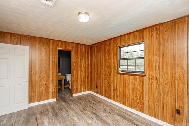 1400 S Rose St, Sheridan, AR 72150 - unfurnished bedroom with wooden walls, baseboards, visible vents, and wood finished floors