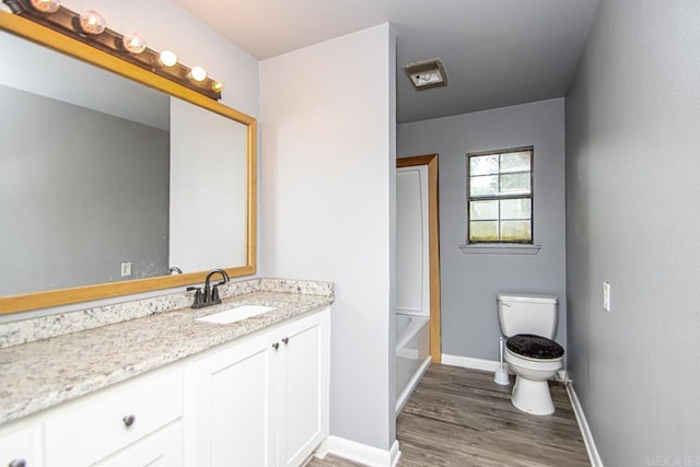1400 S Rose St, Sheridan, AR 72150 - bathroom featuring toilet, wood finished floors, vanity, a washtub, and baseboards