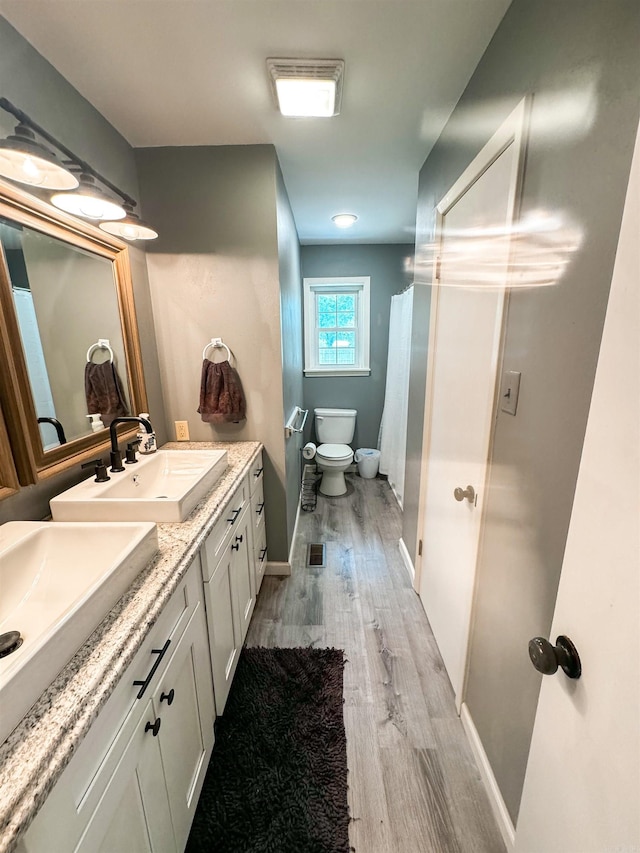 105 Liles, Searcy, AR 72143 - bathroom featuring toilet, baseboards, a sink, double vanity, and wood finished floors
