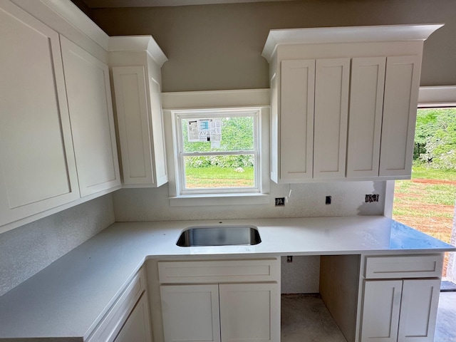kitchen with light countertops, white cabinetry, a healthy amount of sunlight, and a sink