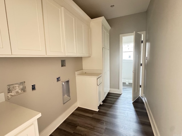 clothes washing area featuring dark wood-style flooring, cabinet space, and baseboards