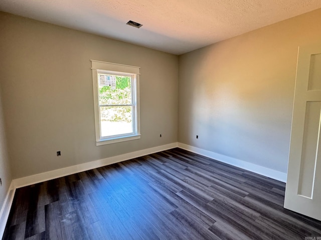 empty room featuring baseboards, visible vents, a textured ceiling, and dark wood-type flooring