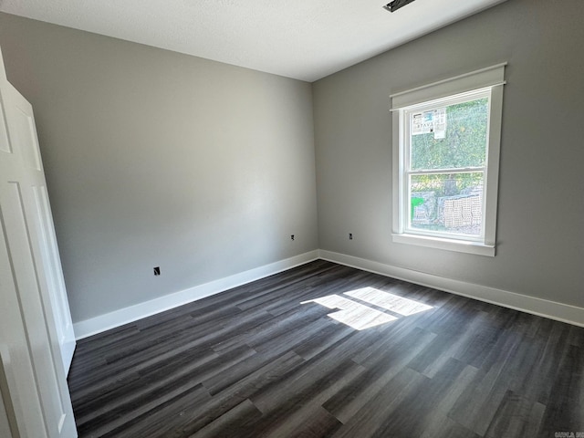 unfurnished room with baseboards and dark wood-style floors