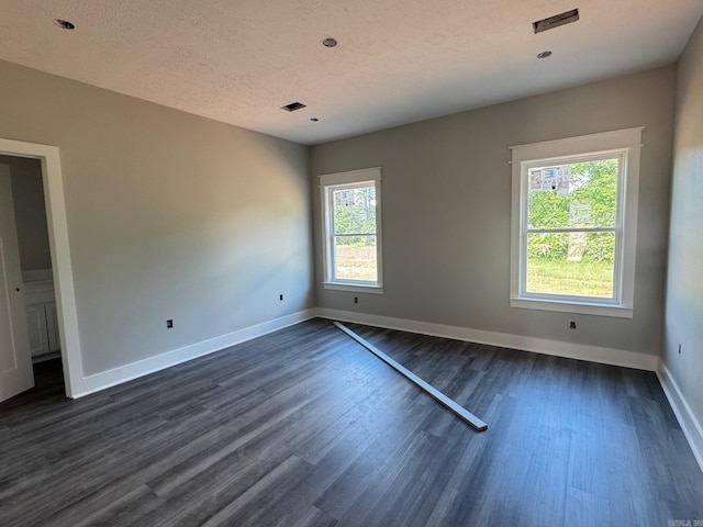 empty room with baseboards, a textured ceiling, and dark wood-type flooring