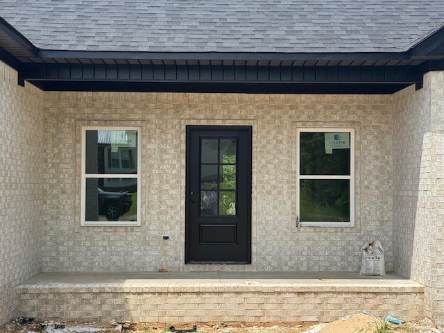 doorway to property with roof with shingles