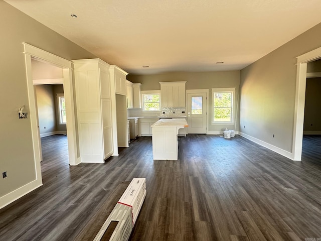 kitchen with plenty of natural light, white cabinetry, a kitchen island, and baseboards