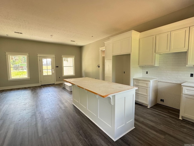 kitchen featuring white cabinetry, a center island, tasteful backsplash, and dark wood-type flooring