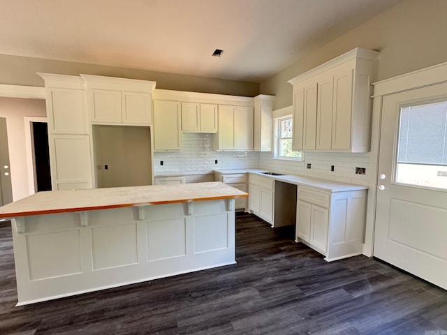 kitchen featuring white cabinetry, backsplash, a center island, and dark wood finished floors