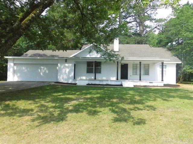 ranch-style home featuring a porch, an attached garage, driveway, a front lawn, and a chimney