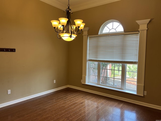spare room with dark wood-style flooring, ornamental molding, baseboards, and a chandelier