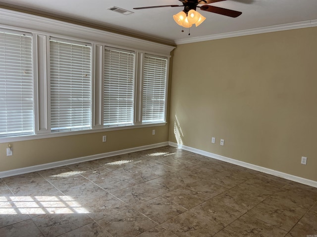 spare room with crown molding, visible vents, baseboards, and ceiling fan
