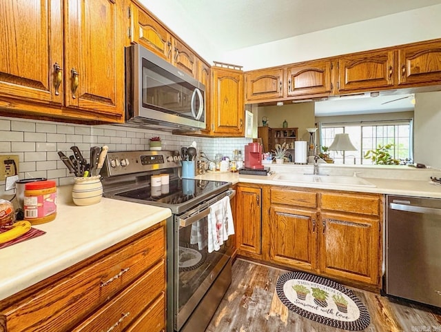 kitchen with light countertops, appliances with stainless steel finishes, brown cabinetry, and a sink