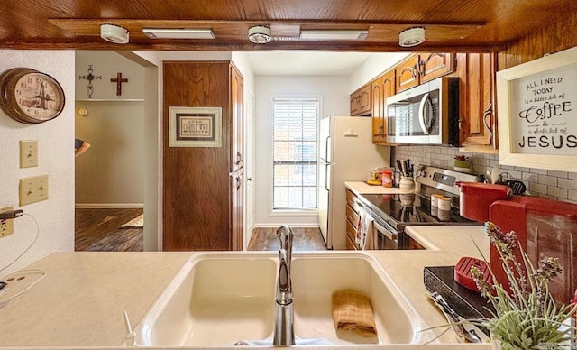 kitchen featuring stainless steel appliances, wood ceiling, decorative backsplash, brown cabinets, and light countertops