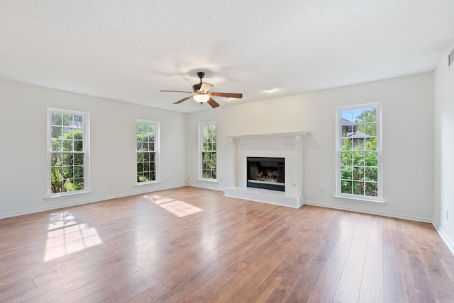 122 Apple Blossom Loop, Maumelle, AR 72113 - unfurnished living room with ceiling fan, light wood-style flooring, a healthy amount of sunlight, and a glass covered fireplace