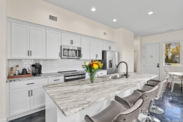 920 Park St, Little Rock, AR 72202 - kitchen featuring white cabinets, appliances with stainless steel finishes, tasteful backsplash, and an island with sink