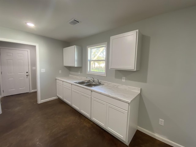 kitchen featuring baseboards, visible vents, a sink, white cabinetry, and light countertops