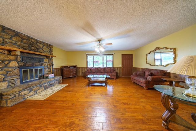 140 Bird Dove Ln, Heber Springs, AR 72543 - living area featuring wood finished floors, a textured ceiling, a fireplace, ceiling fan, and wainscoting