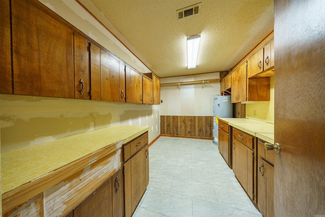 140 Bird Dove Ln, Heber Springs, AR 72543 - kitchen featuring a textured ceiling, a wainscoted wall, brown cabinets, light countertops, and water heater