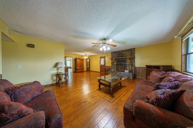 140 Bird Dove Ln, Heber Springs, AR 72543 - living area with a ceiling fan, a textured ceiling, a stone fireplace, visible vents, and hardwood / wood-style flooring