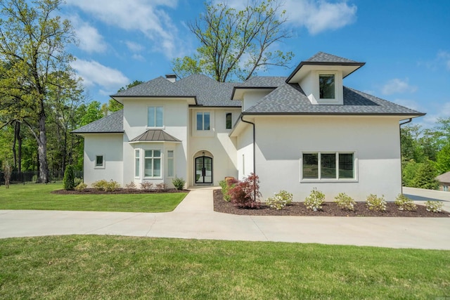 view of front facade featuring stucco siding, roof with shingles, french doors, and a front yard