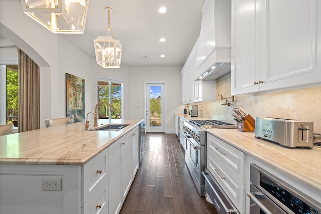 kitchen with a sink, stainless steel appliances, an inviting chandelier, custom exhaust hood, and white cabinets